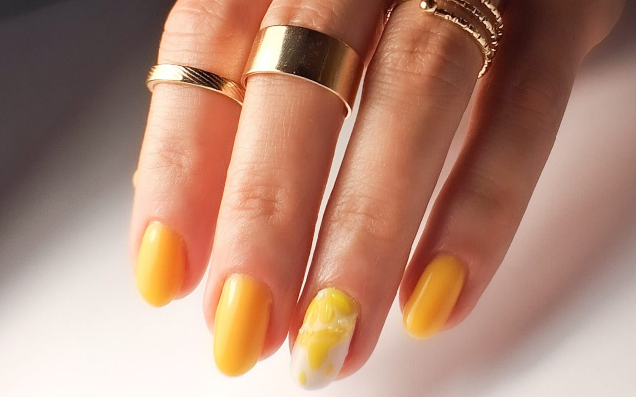 Gele nagels met één accentnagel met bloem